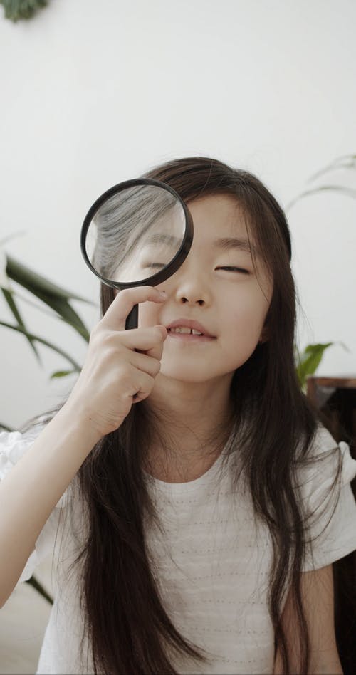 一个女孩在她的左眼附近放一个放大镜 · 免费素材视频