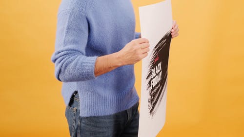 一个穿着蓝色毛衣的男人拿着一张海报 · 免费素材视频