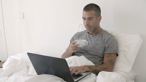 使用他的笔记本电脑时喝咖啡的人 · 免费素材视频