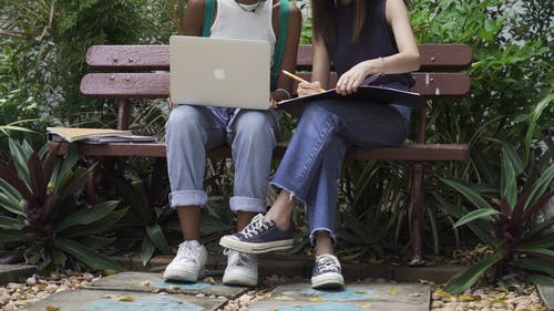 两个学生坐在长凳上，一边讨论他们的笔记 · 免费素材视频