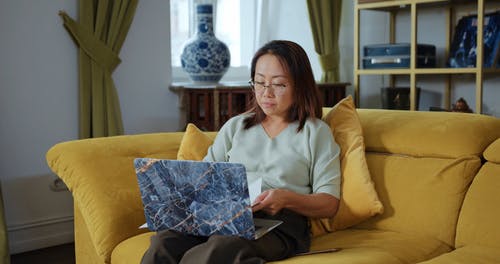 一位妈妈在沙发上使用一台笔记本电脑 · 免费素材视频