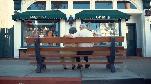 一对老年夫妇坐在人行道的长椅上 · 免费素材视频