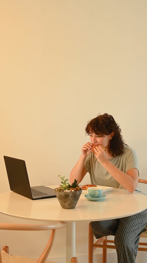 一个女人在用笔记本电脑工作时吃小吃 · 免费素材视频