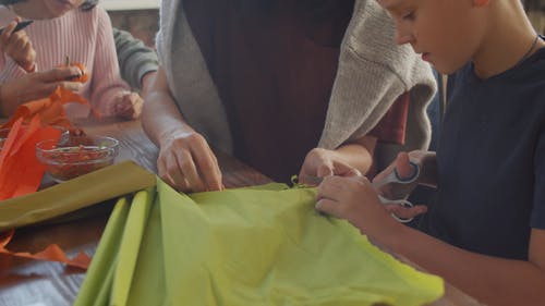 男孩切割一块绿色的布 · 免费素材视频