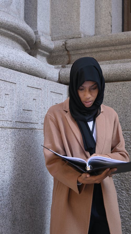 女人看着她的笔记时戴着黑色的头巾 · 免费素材视频