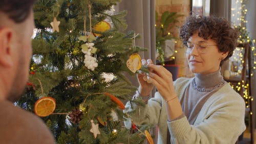 一对夫妇在他们的圣诞树上挂装饰 · 免费素材视频