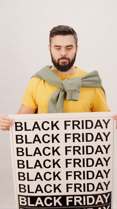 一个男人拿着黑色星期五的海报 · 免费素材视频