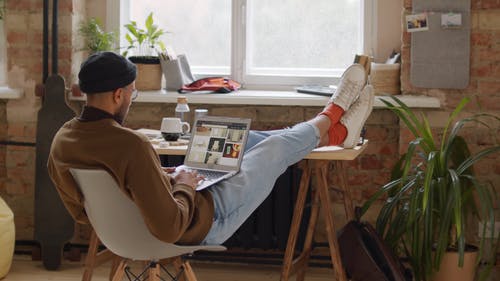 一个人坐在笔记本电脑中浏览照片时舒适地坐着 · 免费素材视频