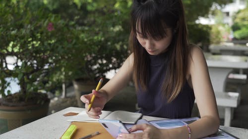 一个女人在她的笔记本上书写时使用她的智能手机 · 免费素材视频