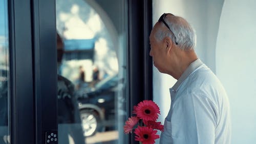 老人捧着鲜花在门前 · 免费素材视频