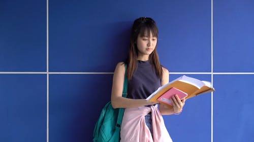 一个女人站在蓝墙旁看着她的笔记 · 免费素材视频