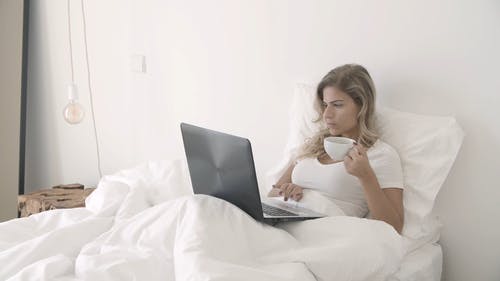 使用她的笔记本电脑时喝咖啡的女人 · 免费素材视频
