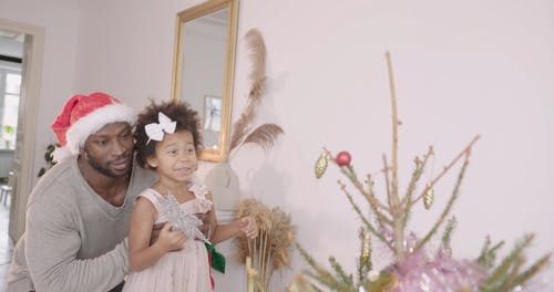 爸爸帮助她的女儿把星星放在圣诞树上 · 免费素材视频