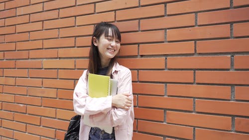 一个女人站在微笑时对砖墙 · 免费素材视频