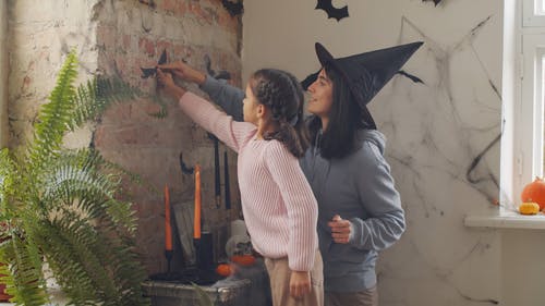 母亲和女儿装饰他们的纸蝙蝠墙 · 免费素材视频
