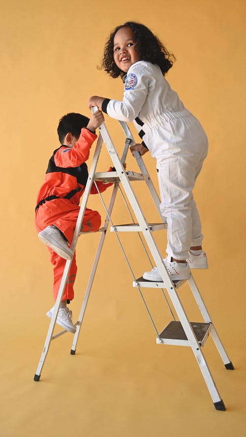 两个孩子穿着太空服服装爬梯子 · 免费素材视频