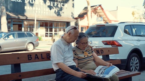 老年夫妇坐在长椅上看报纸 · 免费素材视频