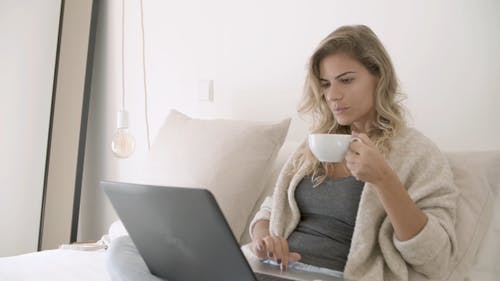 女人忙着喝她的咖啡时使用她的笔记本电脑 · 免费素材视频