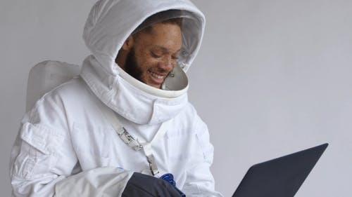 宇航员笑着看着一台笔记本电脑 · 免费素材视频