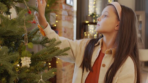 一个年轻的女孩，装饰一棵圣诞树 · 免费素材视频