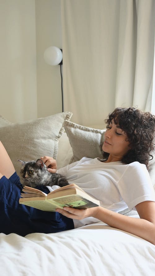 一个女人和她的宠物猫一起读书 · 免费素材视频