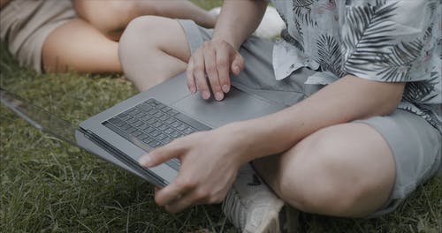 男子坐在草地上，使用一台笔记本电脑 · 免费素材视频