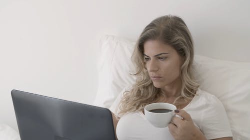 女人喝她的咖啡时使用她的笔记本电脑 · 免费素材视频
