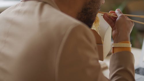 一个人在他的笔记本电脑上工作时吃面条 · 免费素材视频