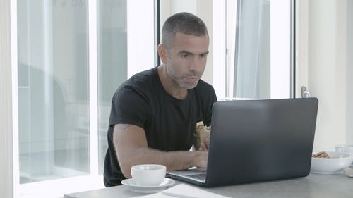 一个人在用笔记本电脑工作时吃早餐 · 免费素材视频