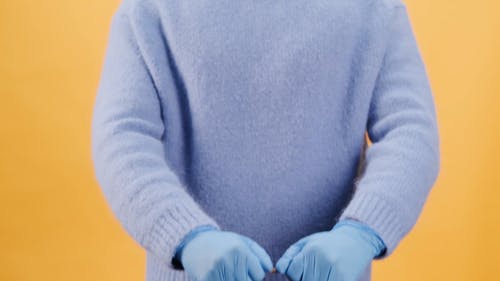 一个穿着蓝色毛衣的人，戴着手套，拿着购物袋 · 免费素材视频