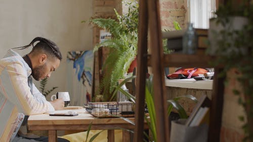 一个年轻人在靠窗的桌子上写字 · 免费素材视频