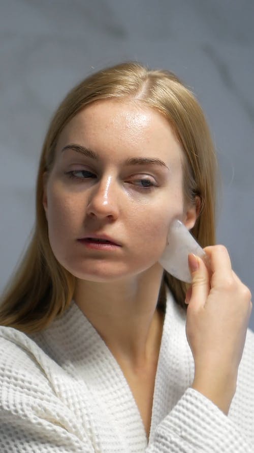 女人在她的脸上使用瓜刮面部工具的视频 · 免费素材视频