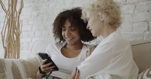 两个女人在使用智能手机时互相交谈 · 免费素材视频