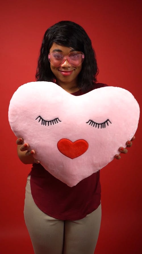 女人抱着一个粉红色的心形枕头 · 免费素材视频