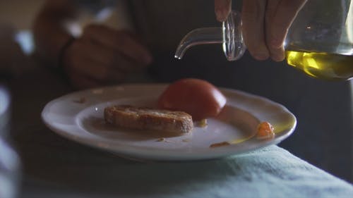 一个人在他的烤面包上倒橄榄油的特写视图 · 免费素材视频