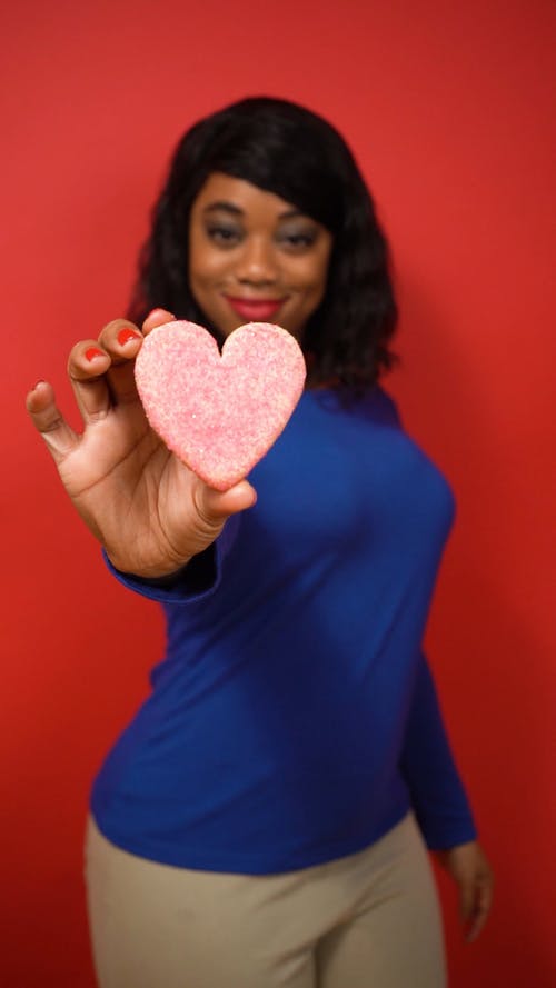 蓝色的长袖衬衫，拿着一个心形饼干的女人 · 免费素材视频