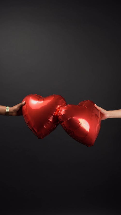 两个人抱着两个红色的心形气球 · 免费素材视频